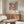 May include: Framed colorful floral art print hanging above wooden credenza in modern living room with white curved chair, round glass coffee table, and floor lamp. The poster features vibrant flowers in coral, pink, and blue tones against dark background with Japanese text at bottom.