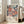 May include: Framed art print featuring stylized floral design with coral, pink, and blue blooms on dark navy background, displayed against white wall next to beige upholstered sofa. Print shows Japanese text and "JAPAN 1987" with decorative flower motifs in soft pastel colors. Light wooden frame complements bright, airy living room setting with large windows.