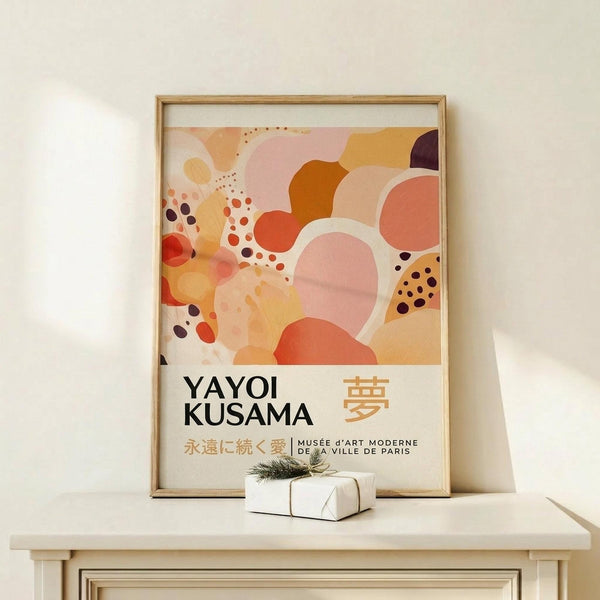 May include: Framed abstract art poster with organic pink, orange, coral and burgundy shapes and dotted patterns, displayed on light wood surface with small wrapped gift box. Wood frame against white wall in minimalist setting.