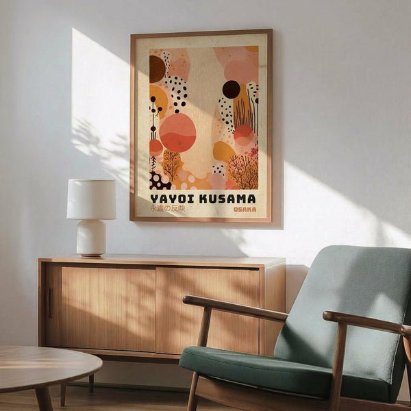May include: Framed abstract art print featuring warm coral, orange, and beige organic shapes with black dots and botanical elements, displayed above a wooden sideboard with white lamp in modern living room with mint green mid-century chair and natural lighting creating geometric shadows on white wall.