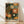May include: Framed art print with colorful abstract floral design featuring radiating sunburst patterns in orange, green, and cream against dark background. Japanese text reads "Yayoi Kusama" and "Tokyo" at bottom. Natural wood frame displays against white wall on light wooden floor with soft shadows.
