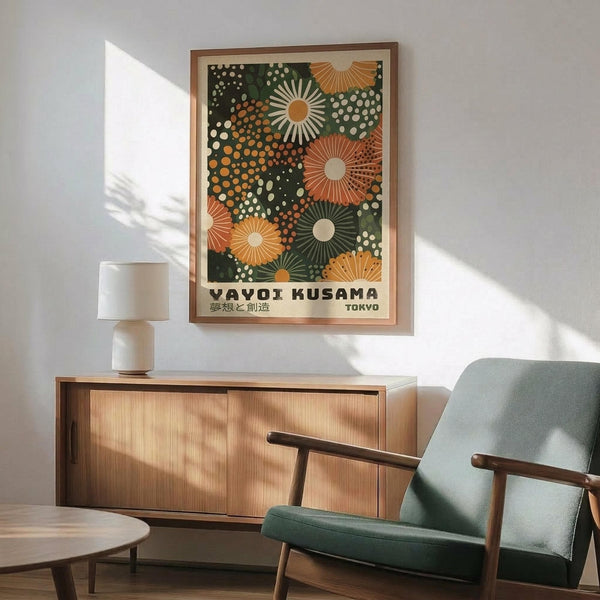 May include: Framed poster with colorful abstract pattern featuring radiating sun motifs and polka dots in green, orange, and cream tones, displayed above a wooden sideboard with table lamp in modern living room setting with mint green upholstered chair and round coffee table