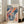 May include: Framed exhibition poster featuring abstract flowing design with coral, navy blue, and teal organic shapes, dots, and swirling patterns. Light wood frame leaning against white wall next to beige upholstered chair in bright, minimalist living room with large windows and natural lighting.