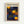 Framed poster with Yayoi Kusama's name at top in black letters, Japanese text below, and "KYOTO" in orange. The artwork features a deep blue background with golden yellow and orange polka dots of varying sizes scattered throughout. Three large circular forms with swirling orange and yellow gradients are positioned across the composition. The print is displayed in a light wooden frame against a white wall.