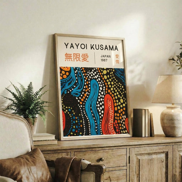 May include: A framed art print featuring flowing abstract patterns in blue, orange, red, and yellow with dotted designs on black background, displayed on a rustic wooden sideboard alongside decorative pottery, books, and a fern plant in a neutral-toned living room setting.