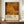 May include: Framed art poster displaying densely packed golden, orange, and amber circles of varying sizes against a dark background, with "YAYOI KUSAMA" text and Japanese characters below. The wooden-framed print sits on a mid-century modern credenza beside a white ceramic vase and books, against cream walls with white trim molding.