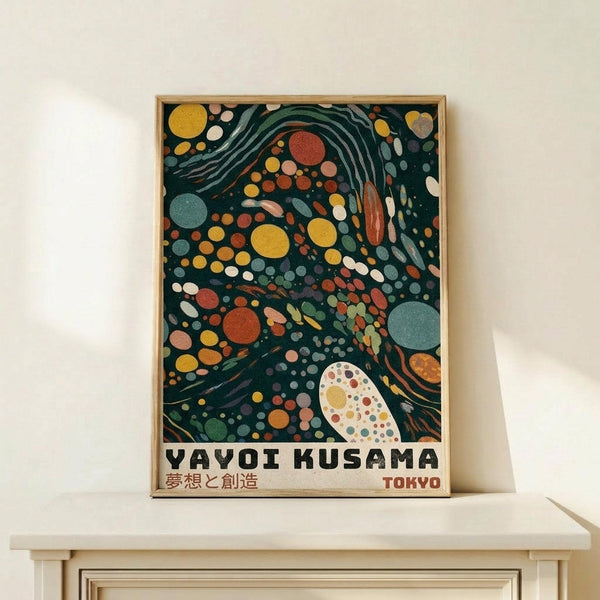 May include: Framed poster with abstract swirling design in dark green background featuring colorful polka dots in yellow, orange, red, and blue tones with flowing wave-like patterns. Text reads "YAYOI KUSAMA" with Japanese characters and "TOKYO" below. Light wood frame sits on pale wooden shelf against cream wall, creating modern minimalist display scene.