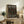 May include: Framed exhibition poster with black background and colorful polka dots in coral, sage green, cream, and peach tones, displayed on rustic wooden sideboard alongside fern plant, ceramic vase, and stacked books in neutral-toned living room setting