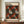 May include: Framed vintage-style exhibition poster with black background featuring repeating pattern of red and white polka-dotted organic shapes resembling shells or pumpkins scattered with small yellow and white dots. Text reads "YAYOI KUSAMA" and "INFINITY SHELL" with Japanese characters and museum details. Brown wooden frame displayed on walnut credenza beside white ceramic vase and stacked books in elegant room with cream walls and white trim.