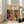 May include: Framed art print leaning against white wall next to beige upholstered chair in bright living room. Poster features colorful abstract pattern with polka dots, organic shapes, and floral motifs in orange, blue, red, and yellow on dark background. Top displays "YAYOI KUSAMA" text with Japanese characters and "JAPAN 1987". Natural wood frame with cream matting, approximately 2-3 feet tall.