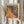 May include: Hands holding a framed art print featuring vibrant polka dot patterns in orange, yellow, and multicolored circles against a dark background, displayed next to dried pampas grass stems against white curtains in natural lighting.