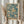 May include: Person in cream sweater holding framed poster featuring jellyfish floating in teal-blue water with flowing tentacles and spots in warm beige tones. Light wooden frame against white curtained window with dried pampas grass. Japanese text visible at bottom of vintage-style travel poster design.