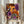 May include: Person in cream sweater holding framed poster with colorful abstract dot art in orange, purple, black and white circular patterns. Japanese text visible at bottom. Dried pampas grass and neutral curtains in background. Light wooden frame around vibrant contemporary artwork with polka dots and concentric circles in psychedelic style.
