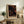 May include: Framed poster with black background featuring scattered circles in orange, coral, and cream tones inspired by Yayoi Kusama's dot art, displayed on rustic wooden sideboard next to fern plant, ceramic vase, and books in warm-toned living room setting
