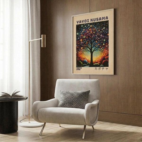 May include: Framed art poster featuring a stylized tree with colorful dotted foliage against a gradient sunset background, displayed on wood paneling above a beige upholstered armchair with geometric patterned pillow, alongside a brass floor lamp and dark side table with open book.