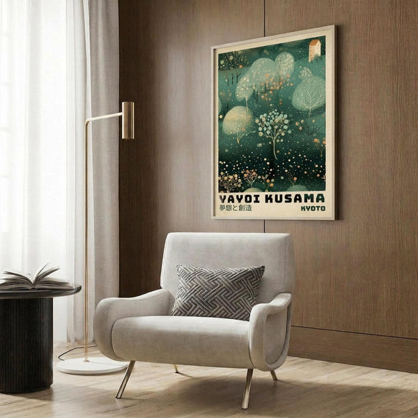 May include: Framed art poster with green forest scene featuring trees, leaves, and dots in Kusama's signature polka dot style, displayed on wood-paneled wall above cream upholstered armchair with geometric patterned pillow, brass floor lamp, and dark round side table with open book in modern living room setting.