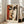 May include: Framed cubist-style portrait poster featuring abstract face with geometric shapes in warm tones of orange, brown, and cream, leaning against white wall next to beige upholstered chair in bright, naturally-lit room with large windows