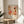 A framed poster of a colorful abstract artwork is displayed on a wooden table in a room with a white couch and a plant in the background.