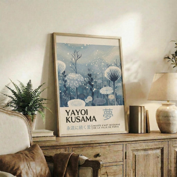 A framed poster of a snowy landscape with flowers hangs on a wall, accompanied by a lamp, a plant, and some books.
