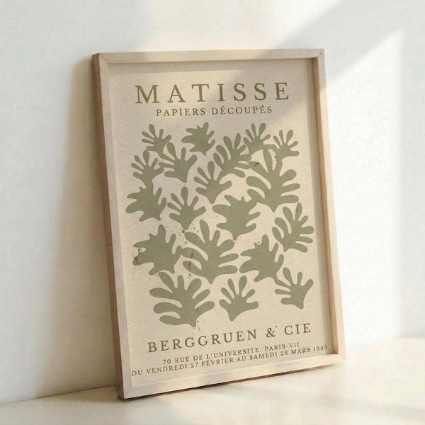 The image is a framed poster featuring a repeating pattern of green leaf-like shapes, with the text "MATISSE PAPiers D'ECOUPS" and "BERGGRUEN & CIE" printed on it.