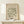 a framed poster of the M.C. Escher's "Matisse" artwork, which is a collection of abstract artworks. The poster is displayed on a white shelf, and there is a small white gift box placed on the shelf as well.