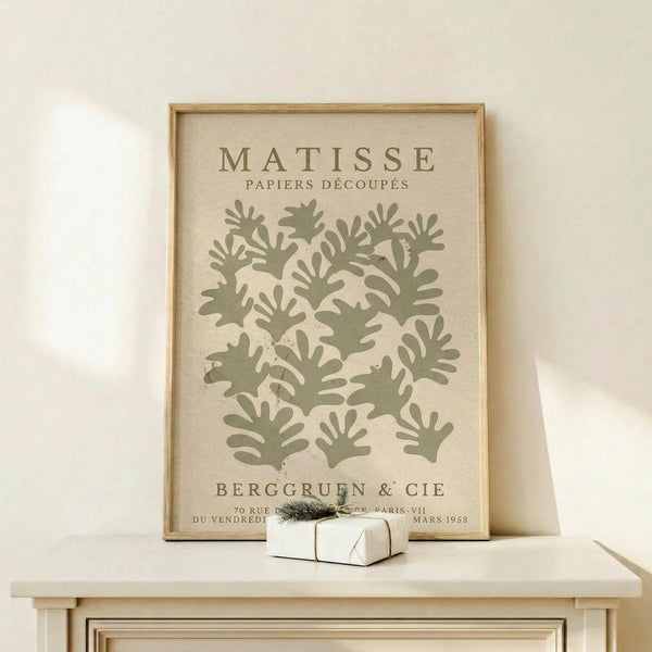 a framed poster of the M.C. Escher's "Matisse" artwork, which is a collection of abstract artworks. The poster is displayed on a white shelf, and there is a small white gift box placed on the shelf as well.