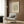 a modern living room with a white armchair, a floor lamp, and a framed poster of the famous artist M.C. Escher.