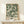 a framed poster of a floral pattern with a white frame, displayed on a white shelf or table.