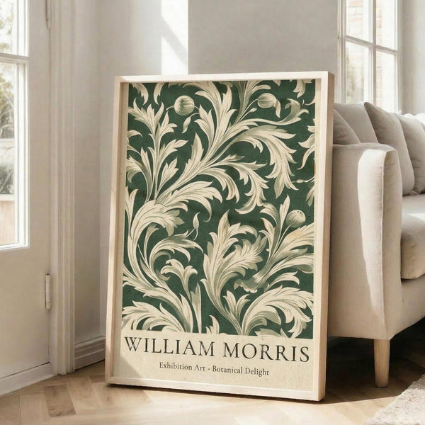 A framed poster of a botanical design with a green and white color scheme, displayed on a wooden floor next to a white couch.