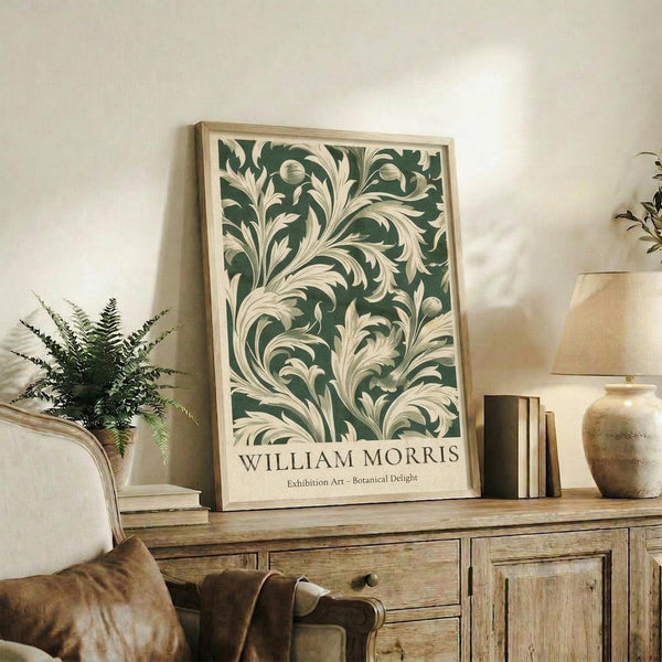 a framed poster of a green and white floral pattern, placed on a wooden cabinet or shelf in a room with a lamp and other decorative items.