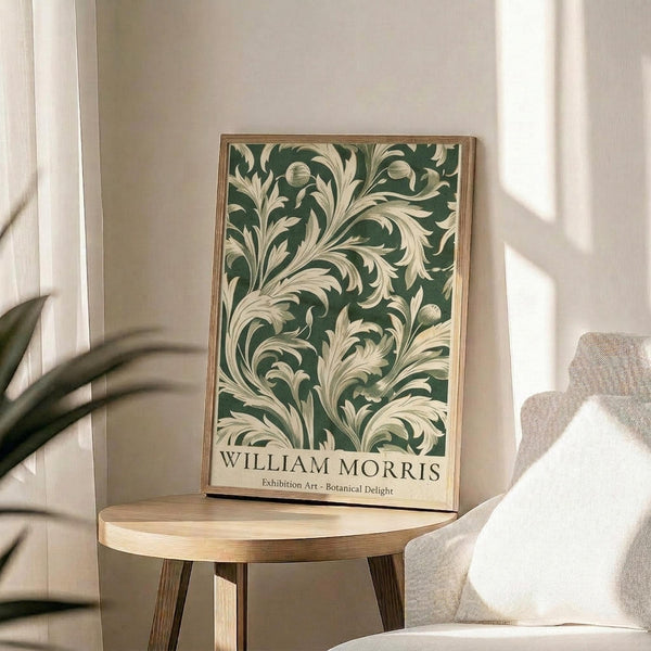 a framed poster of a floral pattern on a wall, placed on a small round table in a room with a white chair and a plant in the background.