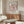 a living room with a large poster of the painting "Matsisse" hanging on the wall above a wooden cabinet. The cabinet has a glass top, and there is a white sofa in the room.