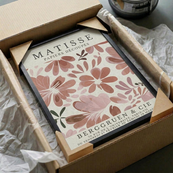 a framed poster of the work "MATISSE" by the artist Frida Cie, which is a large floral print. The poster is displayed in a cardboard box, and there is a clear plastic sleeve on the box.