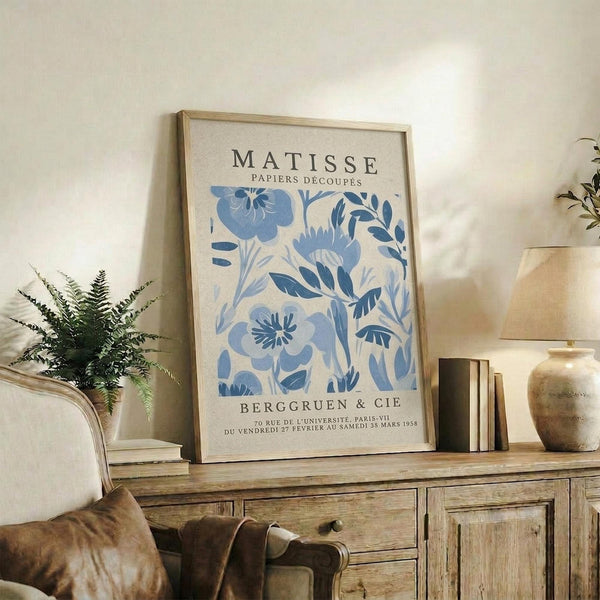 a framed poster of the famous painting "Matsisse" by the artist Edouard Manet, displayed on a wooden shelf in a living room setting.