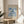 a framed poster of the Métisse art movement, with a floral design in blue and white colors. The poster is displayed on a wooden table, and there is a white chair visible in the background.