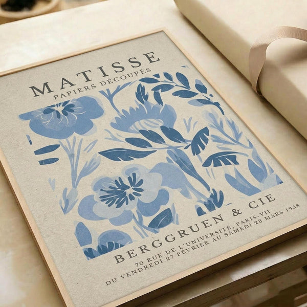 a framed poster with a floral pattern in shades of blue and white. The poster is titled "MATISSE PAPiers DECOUPES" and includes the text "BERGRUEN & CIE" along with the location "BERGRUEN & CIE" and the date "28 MARS 1958".