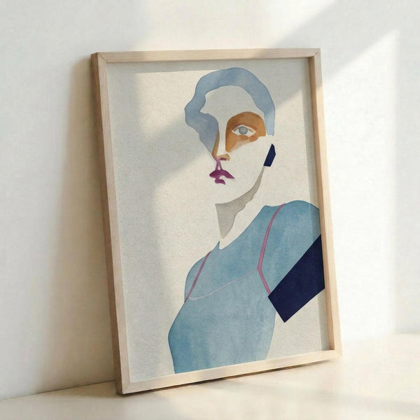 Abstract portrait artwork in minimalist style featuring a figure with geometric color blocks in blue, orange, and burgundy tones. The face is stylized with asymmetrical features including one visible eye, orange skin tone on half the face, and blue hair outline. Figure wears a light blue garment with dark navy accent. Artwork is displayed in a natural wood frame against a white wall, showing subtle shadows from natural lighting.