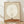 May include: Framed minimalist poster print featuring a small silhouetted figure sitting on an orange-brown curved landscape beneath a large white crescent moon on a beige background. Light wooden frame sits on wooden floor against white wall with soft natural lighting and shadows.