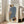 May include: Large framed abstract fashion print leaning against white wall in bright living room. Artwork shows minimalist figure in blue striped top and leopard print skirt holding dark purse. Light wood frame, beige sofa visible, natural sunlight streaming through windows onto hardwood floors.
