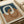 May include: Abstract art print with interlocking curved rings in cream, terracotta orange, and navy blue colors, displayed in a light wood frame on white wrapping paper beside neutral ribbon