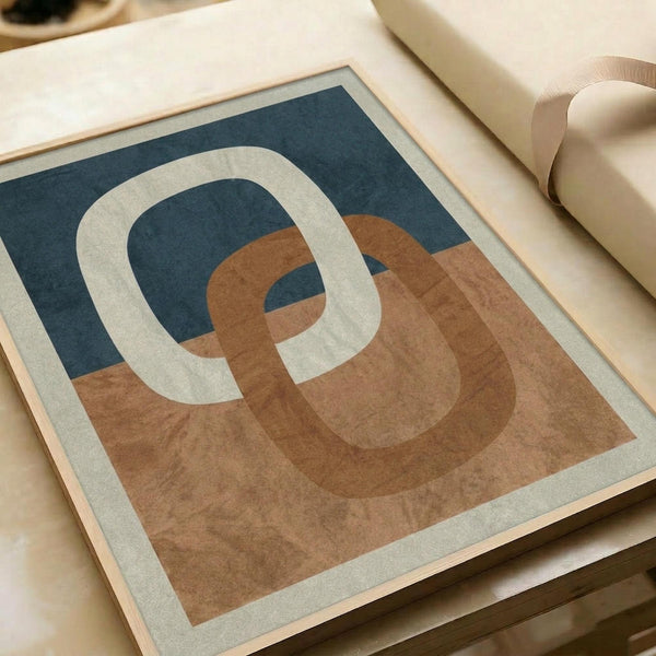 May include: Abstract art print with interlocking curved rings in cream, terracotta orange, and navy blue colors, displayed in a light wood frame on white wrapping paper beside neutral ribbon
