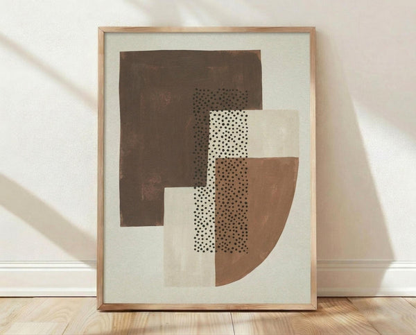 May include: Framed abstract geometric art print leaning against white textured wall on light wood floor. Artwork features overlapping shapes in brown, beige, and cream tones with black dotted patterns creating layered composition. Natural wood frame with white matting. Soft shadows cast across scene from natural lighting.