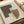 May include: Framed abstract art print with earthy geometric shapes in brown and terracotta tones, featuring dotted stippled textures overlaying curved and angular forms, displayed on a light wooden surface next to neutral colored paper rolls in soft natural lighting
