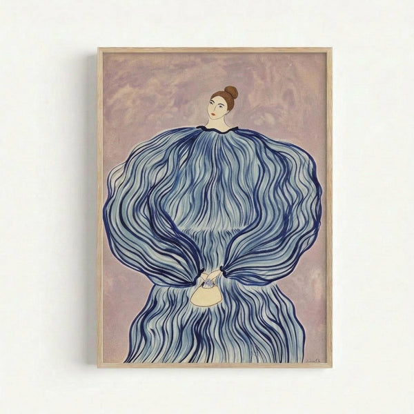 Framed artwork showing a woman with a hair bun wearing a dramatic flowing blue dress or cloak with wavy, undulating fabric that billows around her entire body. She holds a small yellow handbag. The background features soft purple and pink tones with a cloudy, ethereal quality. The piece has a stylized, Art Deco-influenced aesthetic with flowing lines and is displayed in a light wooden frame against a white wall.