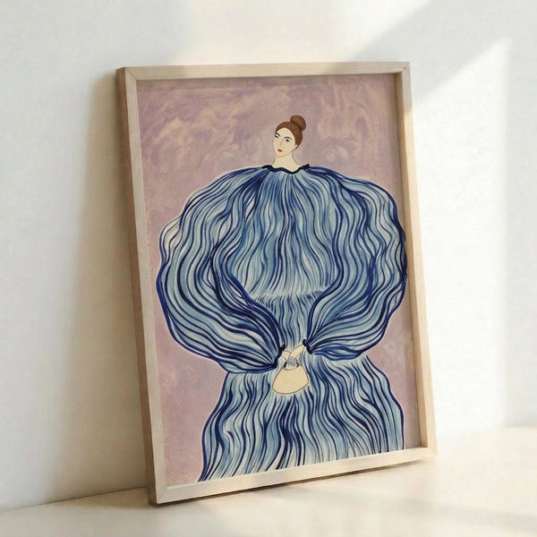 Framed art print featuring a woman with brown hair in a bun, wearing an elaborate flowing blue dress with wave-like patterns that billows dramatically around her body. She holds a small yellow purse. The background is soft purple-pink with subtle textures. The artwork is displayed in a light wooden frame against a white wall, showing the piece at an angle that reveals the frame's depth.
