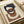Abstract geometric print with interlocking curved and angular shapes in navy blue and rust brown on cream background. The weathered, textured design shows vintage-style distressing. Print lies flat on light wooden surface next to rolled kraft paper, creating an artistic workspace scene.