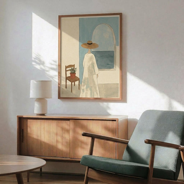 May include: Mid-century modern living room with wooden credenza, sage green upholstered armchair, and white table lamp. Framed artwork shows woman in wide-brimmed hat and flowing white dress standing by window overlooking blue sea, with wooden chair and potted plant nearby. Warm sunlight casts geometric shadows across white wall.