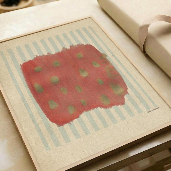 May include: Framed abstract art print displayed on white bedding next to cream pillows. The artwork features a coral red irregular shape with scattered olive green dots against a background of soft blue and cream vertical stripes. The piece has a painterly, textured appearance with rough brushstroke edges and is presented in a simple light wood frame.
