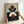 May include: Person's hands holding a framed abstract geometric art print against a white wall. The artwork features layered semicircles and circles in terracotta orange, cream, navy blue, and brown tones arranged in a balanced composition. The print is displayed in a light wood frame and shows textured, matte finish details.
