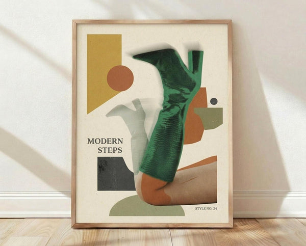 May include: Framed abstract art print featuring colorful geometric shapes and forms in green, orange, yellow, and brown tones with "MODERN STEPS" text, displayed in light wood frame against white textured wall on wooden floor with natural lighting creating soft shadows